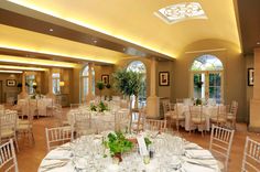 a banquet room with tables and chairs set up for an event or function, complete with white linens and green centerpieces