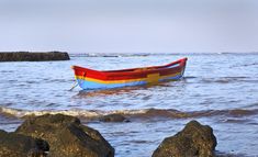 a red and yellow boat sitting on top of the ocean