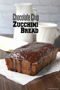 chocolate chip zucchini bread on a wooden table with coffee cups in the background