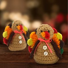 two small crocheted turkeys sitting on top of a wooden table next to each other