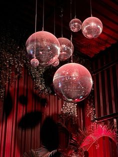 several disco balls hanging from the ceiling in a room with red walls and palm trees