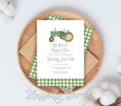 a green and white tractor birthday party card on top of a wooden plate next to cotton balls