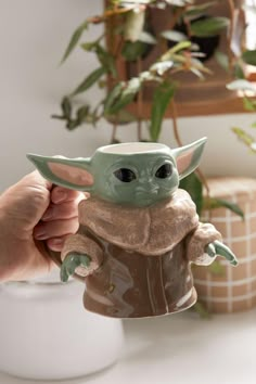 a person holding a baby yoda toy in their hand