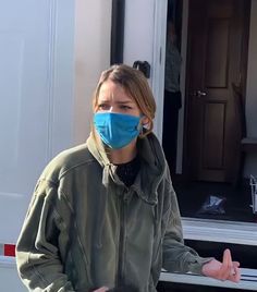 a woman wearing a face mask standing in front of a trailer