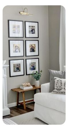 a living room with white furniture and framed pictures on the wall above the couches