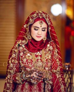 a woman in a red and gold bridal outfit is looking down at her hands