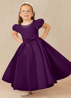 Have your flower girl dressed to impress your friends and family while she wears our matte satin little ballgown, Jewel. Her neckline is jeweled with hand sewn beading, puff sleeves, and a beautiful bow belt that sits atop a full box-pleat tea length skirt. We have matching pearls at the sleeves and a removable back bow. Dark Purple Gown, Satin Flower Girl Dresses, Grape Flower, Purple Flower Girls, Tea Length Flower Girl Dress, Purple Flower Girl Dress, Dark Purple Dresses, Frocks For Kids, Purple Girls Dress