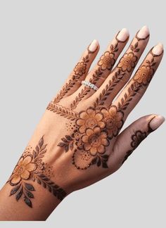 a woman's hand with henna tattoos on it and flowers in the middle