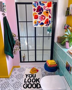 a bathroom with a rug that says you look good on the floor next to a toilet