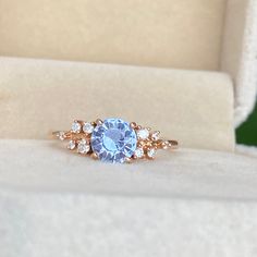 an engagement ring with a blue stone surrounded by white diamonds in a velvet presentation box