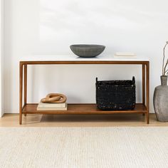 a table with a basket, vase and book on it next to a white wall