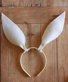 a white bunny ears headband on top of a wooden floor