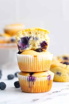 three blueberry muffins stacked on top of each other with one bite taken out