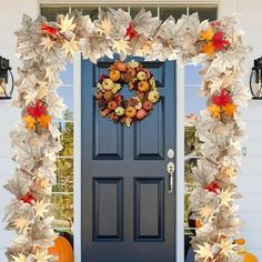 a front door decorated with fall leaves and pumpkins