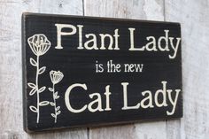 a wooden sign that says plant lady is the new cat lady on it's side