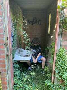 a boy sitting in an overgrown out building