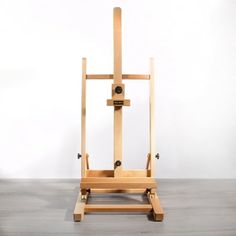 a wooden easel sitting on top of a hard wood floor next to a white wall