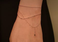 a woman's hand with a black beaded bracelet on her wrist and a diamond necklace hanging from it