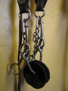 a pair of black leather handcuffs hanging from the side of a wall with chains attached to it