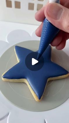 someone is decorating a star cookie with blue icing