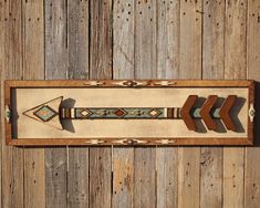 an arrow made out of wood on top of a wooden wall mounted plaque with arrows