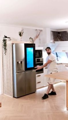 a man standing next to a refrigerator in a kitchen