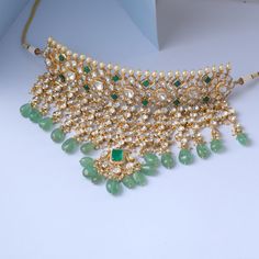 Description This silver choker necklace by Paksha is expertly created from an array of Moissanite stones in mixed classic cuts and high-quality CZ stones. Finished with a gold-tone plated, highlighting its beautiful hues and rich yellow tones, this necklace makes a grandeur and luxury statement. It is crafted with beautiful green precious beads. This choker necklace is part of the Rasika family, designed by Paksha experts. Style this on your special day for grand rich look. Product Information M Traditional Diamond Necklace With Stones, Traditional Cubic Zirconia Gemstone Necklaces, Gold Jewelry With Stones For Diwali, Hand Set Cubic Zirconia Choker Necklace, Hand-set Cubic Zirconia Choker Necklace, Festive Cubic Zirconia Stone Necklaces, Festive Cubic Zirconia Stone Necklace, Temple Jewelry Style Choker Necklace For Receptions, Temple Jewelry Style Choker For Receptions