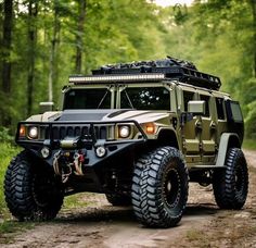 an army vehicle driving down a dirt road in the woods