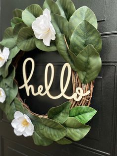 a wreath with the word hello painted on it and some white flowers hanging from it