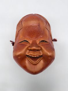 a wooden mask that has been carved into the shape of a smiling person's face