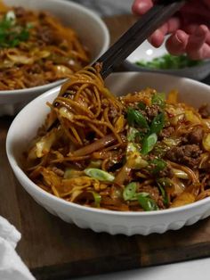 two bowls filled with noodles and meat on top of a wooden cutting board