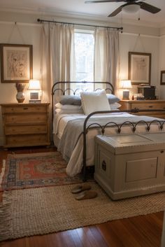 a bedroom with a bed, chest and ceiling fan