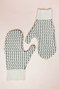 an oven mitt made out of black and white knitted material on a pink background