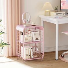 a pink computer cart with books and headphones on it in front of a desk