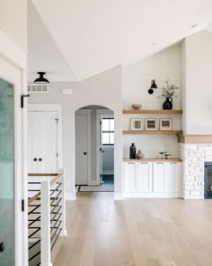 an open kitchen with white cabinets and wood flooring is seen from the hallway to the living room