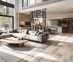 a living room filled with lots of furniture and large windows next to a dining area