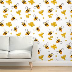 a white couch sitting in front of a wall with honeycombs and bees on it