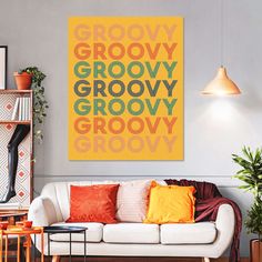 a living room with a white couch and yellow poster on the wall next to potted plants