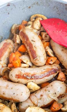 sausages, carrots and mushrooms cooking in a pan with a red spatula