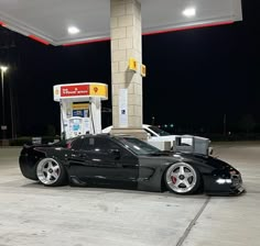 a black sports car parked in front of a gas station