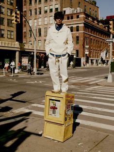 a man standing on top of a yellow box in the middle of a city street