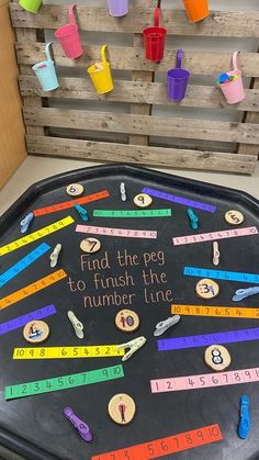 a black tray with writing on it that says find the pegs to finish the number line