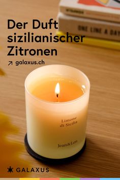 a candle sitting on top of a wooden table next to some books and a book