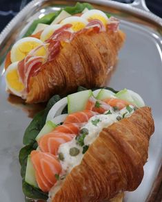 two croissants filled with meat and vegetables on a silver platter next to each other