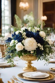 an elegant centerpiece with blue and white flowers on a gold pedestal sits atop a table