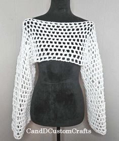 a mannequin torso wearing a white crochet shrugr top with black dots