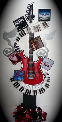 a red guitar sitting on top of a black and white piano with music memorabilia around it