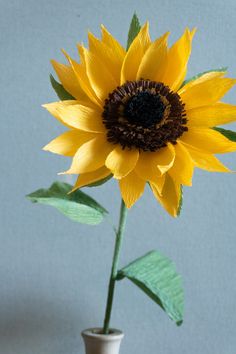 a yellow sunflower in a small white vase