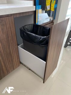 a trash can in the corner of a kitchen with a sink and cabinets behind it