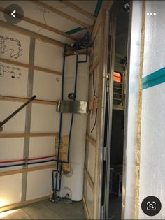 the inside of a storage room with pipes and wires attached to the wall next to an open door